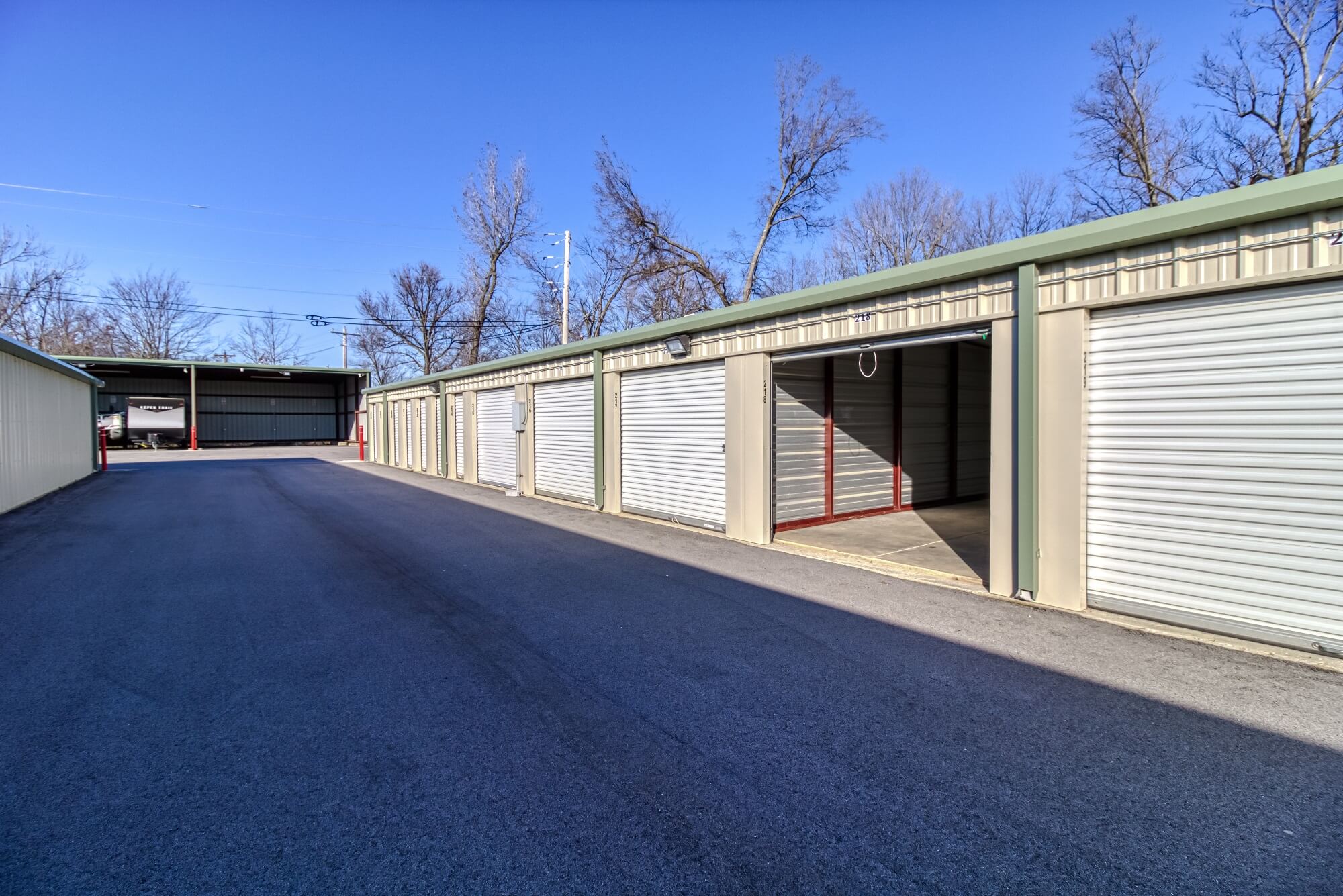 Drive-up storage units with white doors. One is open to reveal the inside